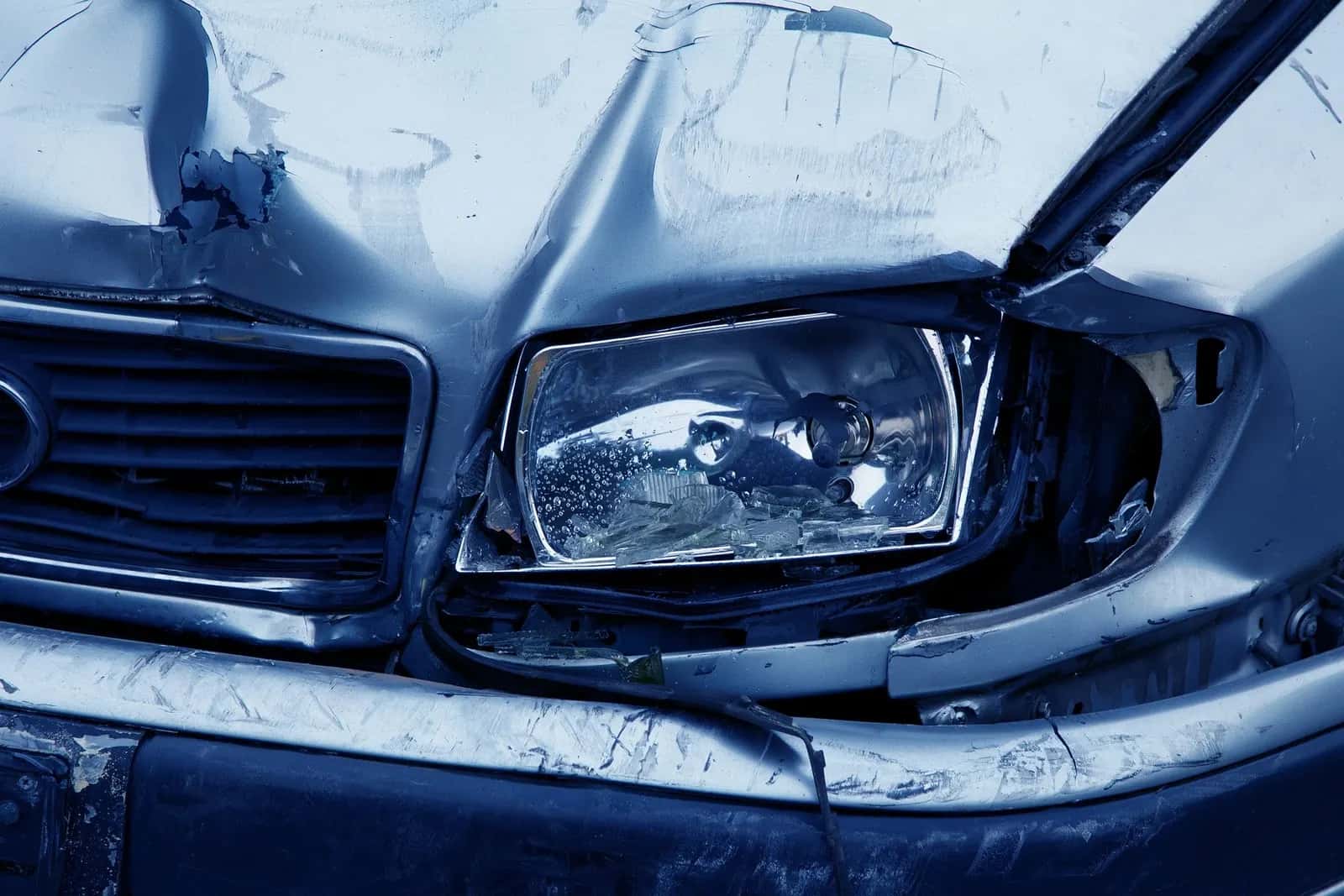 Eingedrückte Fahrzeugfront mit zerbrochenem Scheinwerfer nach einem Unfall